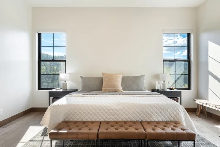 Bright interior with wood-finish flooring, two large multi-pane windows, and high ceilings