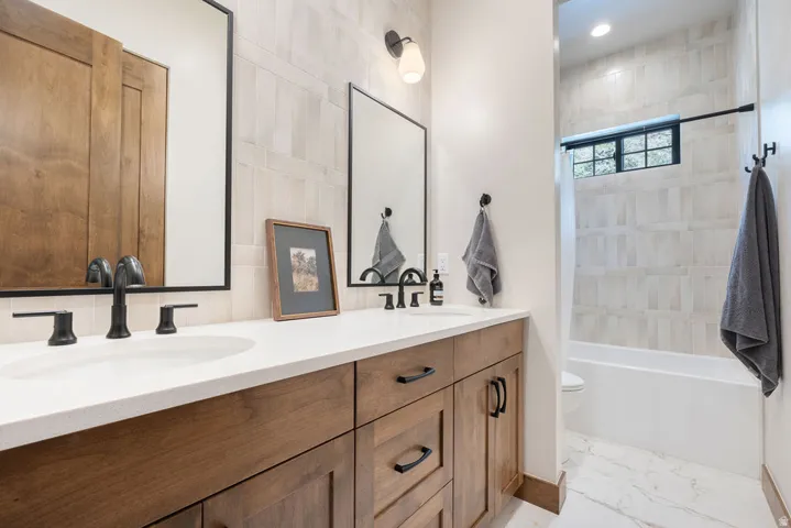 Dual vanity with wood-finish cabinetry and matte black fixtures