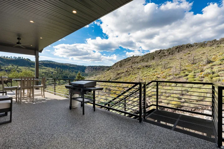 Covered outdoor patio with a speckled aggregate surface, recessed lighting, and a ceiling fan