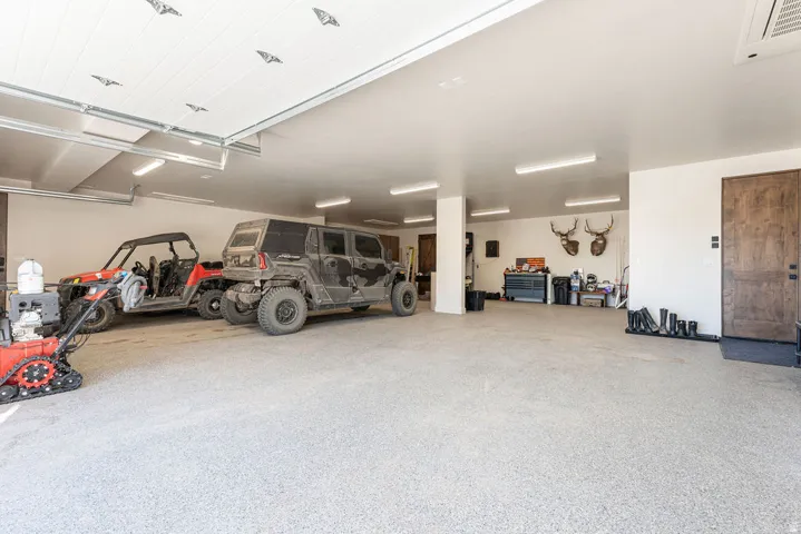 Spacious garage featuring a durable epoxy floor coating, multiple fluorescent light fixtures, and a wood-panel entry door