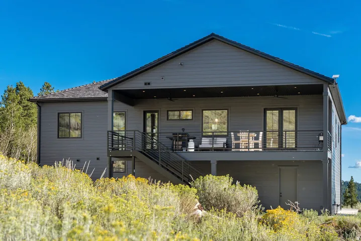 Expansive upper deck with black metal railing, covered patio space with recessed lighting and ceiling fans, and ground-level door access