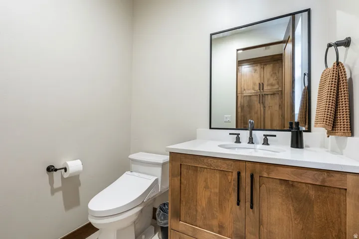 Wood-finish vanity with dual-door cabinetry, white countertop, and rectangular undermount sink