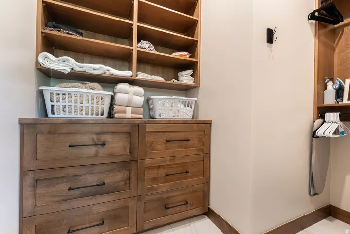 Built-in wood-finish cabinetry with multiple drawers, open shelving, and integrated hanging space