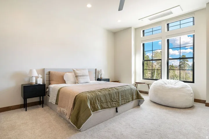 Large windows with black frames, recessed ceiling lighting, a ceiling fan, light neutral-toned carpeting, and a built-in air conditioning unit