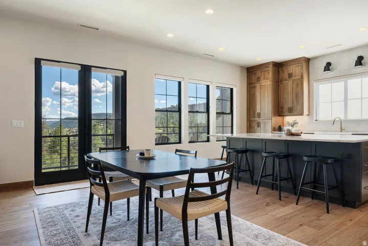 Open-concept kitchen and dining area featuring wood-finish flooring, recessed lighting, and black-framed windows