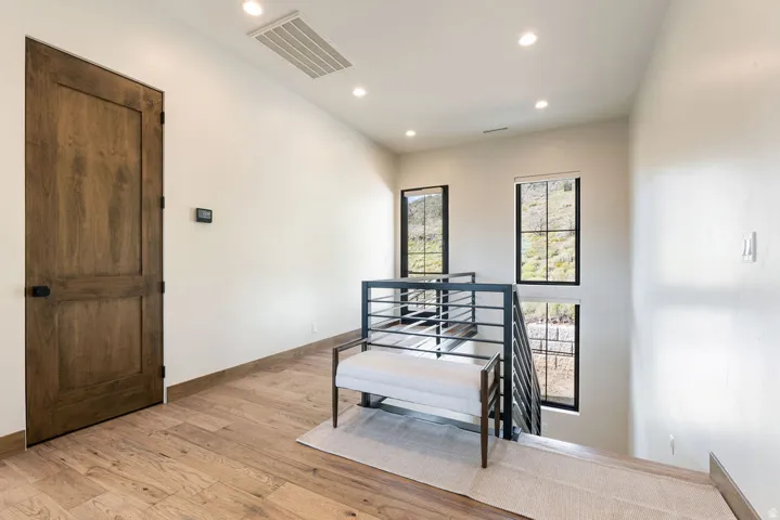 Wood-finish flooring, recessed lighting, and a modern metal railing