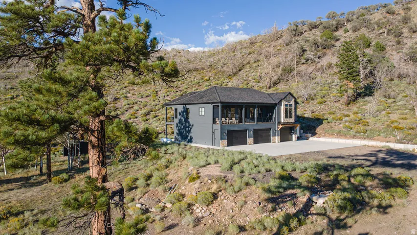 Modern exterior with dark siding, a multi-car garage, and a covered patio