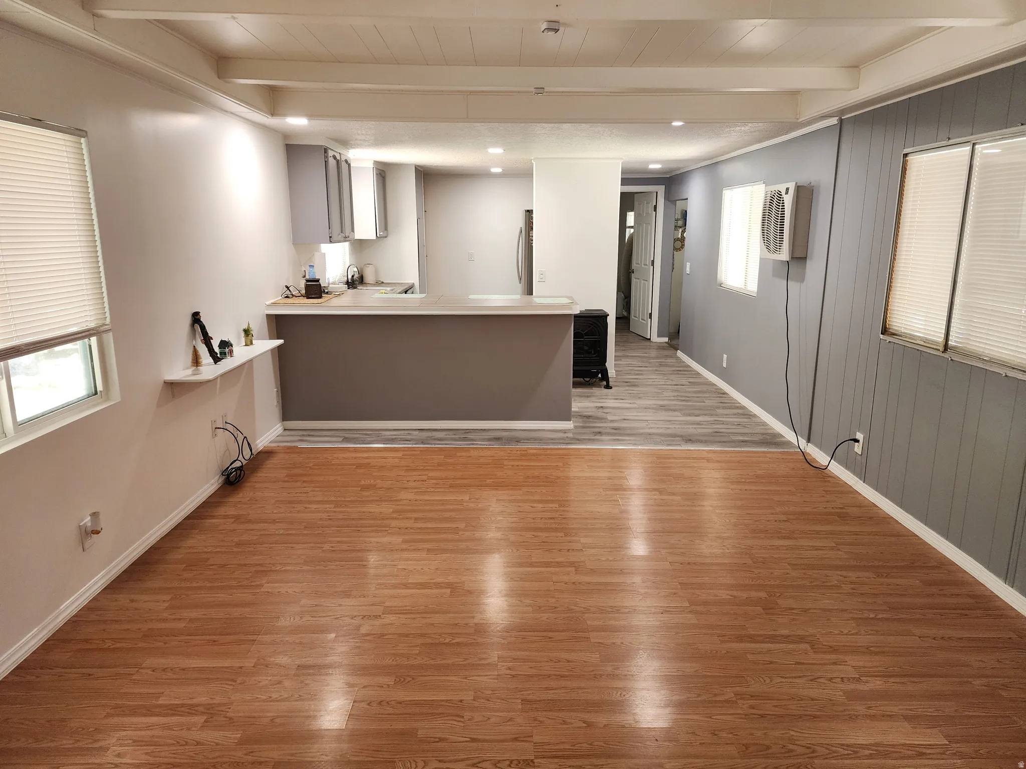 Open concept living area with wood-finish flooring, recessed lighting, and exposed ceiling beams