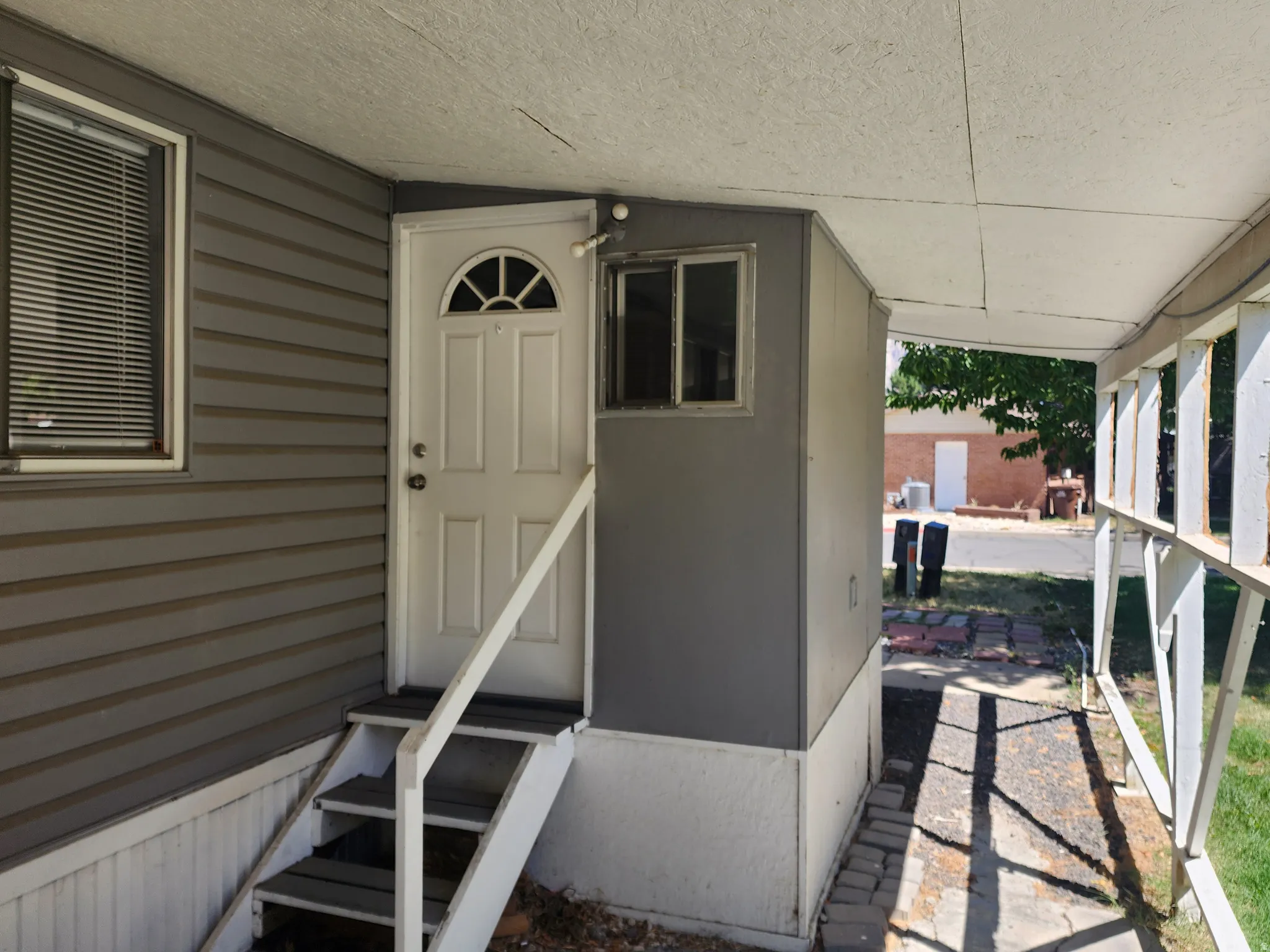 Exterior entry featuring a paneled door with an arched transom, a window with blinds, and steps with a handrail