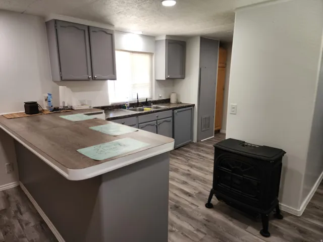 Wood-finish flooring throughout, gray cabinetry with modern hardware, and a built-in kitchen island with wood-finish countertop