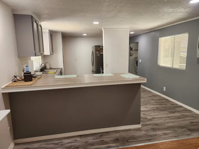 Kitchen featuring gray upper cabinetry, recessed lighting, wood-finish flooring, and a breakfast bar with a light wood-finish countertop