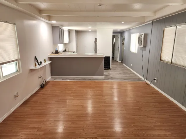 Open concept living area with wood-finish flooring, recessed lighting, and exposed ceiling beams