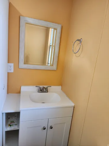White vanity with an integrated sink, brushed nickel faucet, and a framed mirror