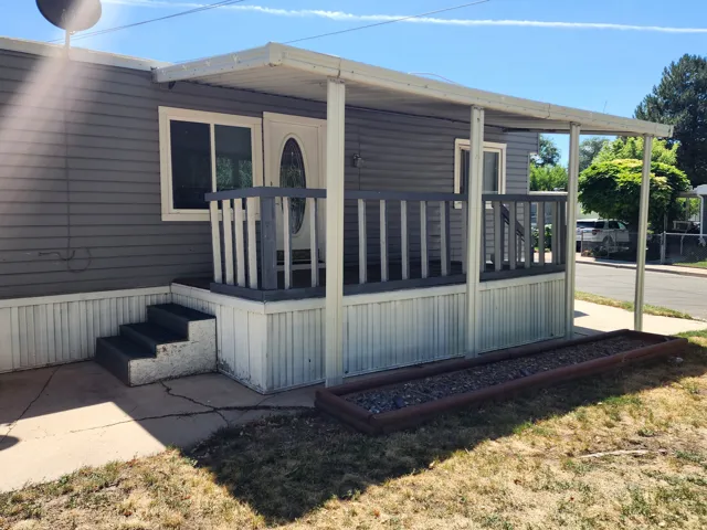 Exterior featuring gray horizontal siding and a covered front porch with white railing