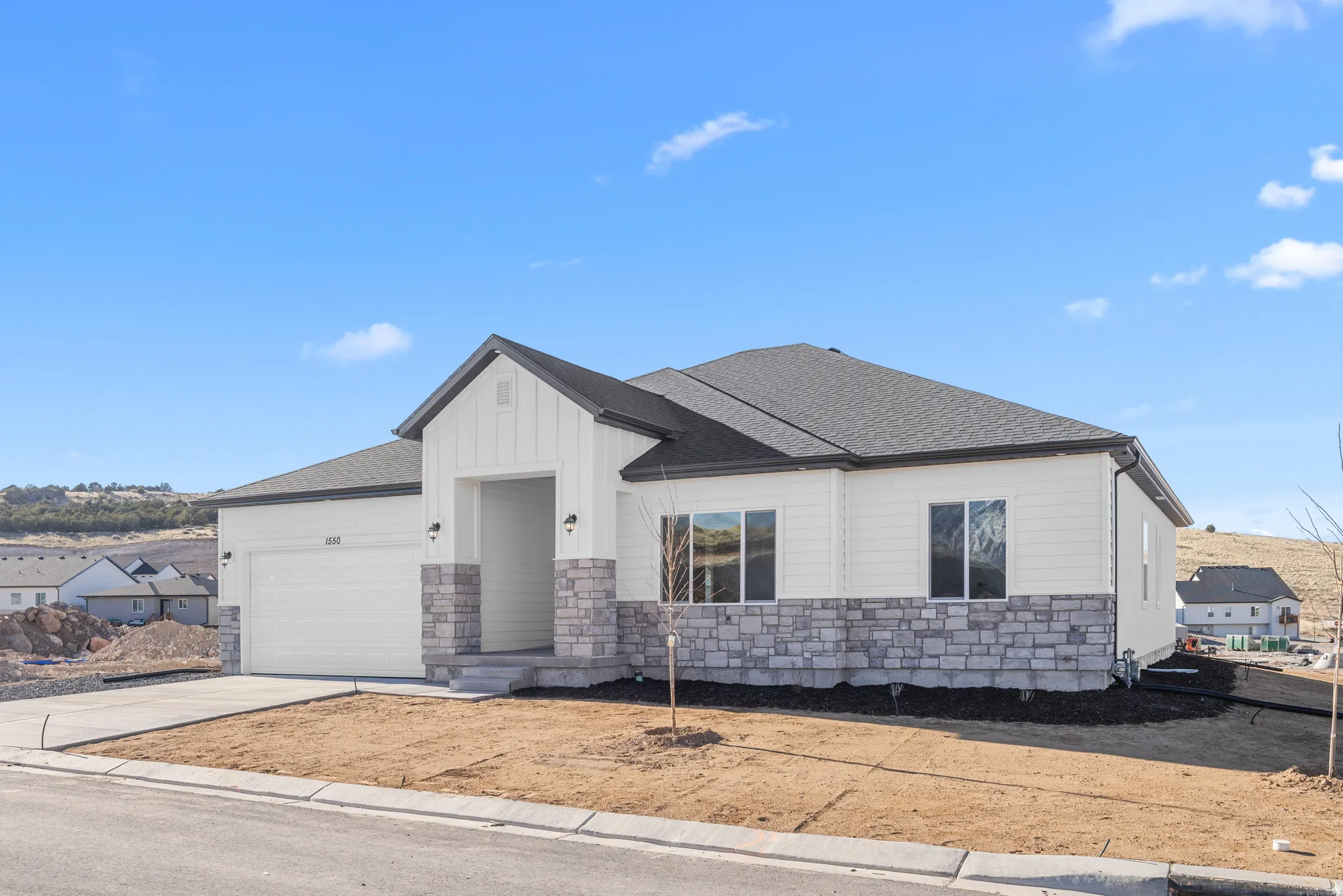 White exterior siding with board-and-batten accent, gray stone veneer, and dark roof shingles