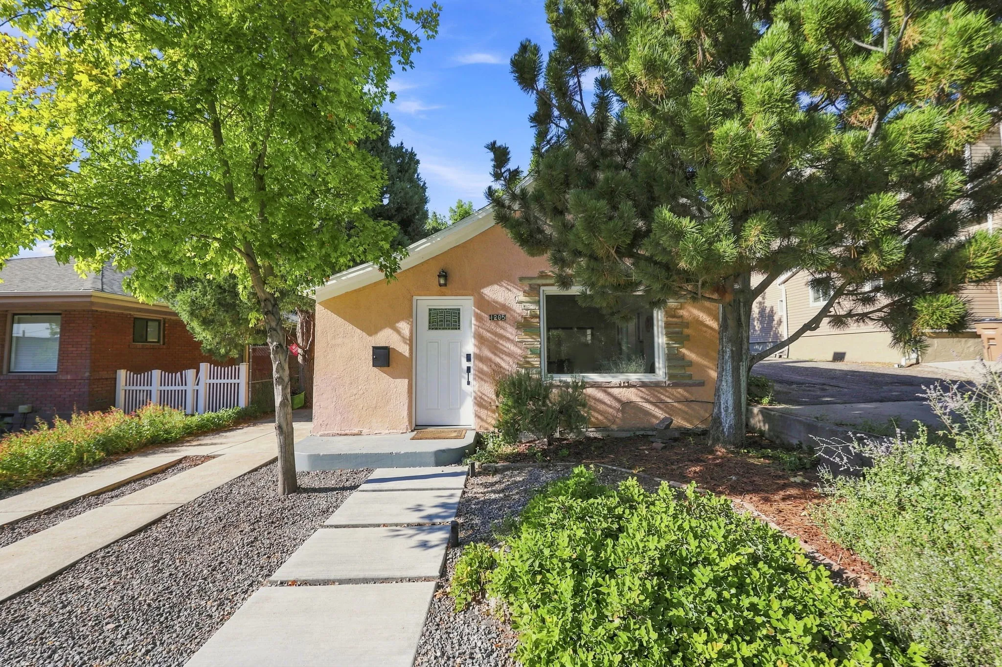 Stucco exterior with a white entry door, an accent window, and a concrete paver walkway