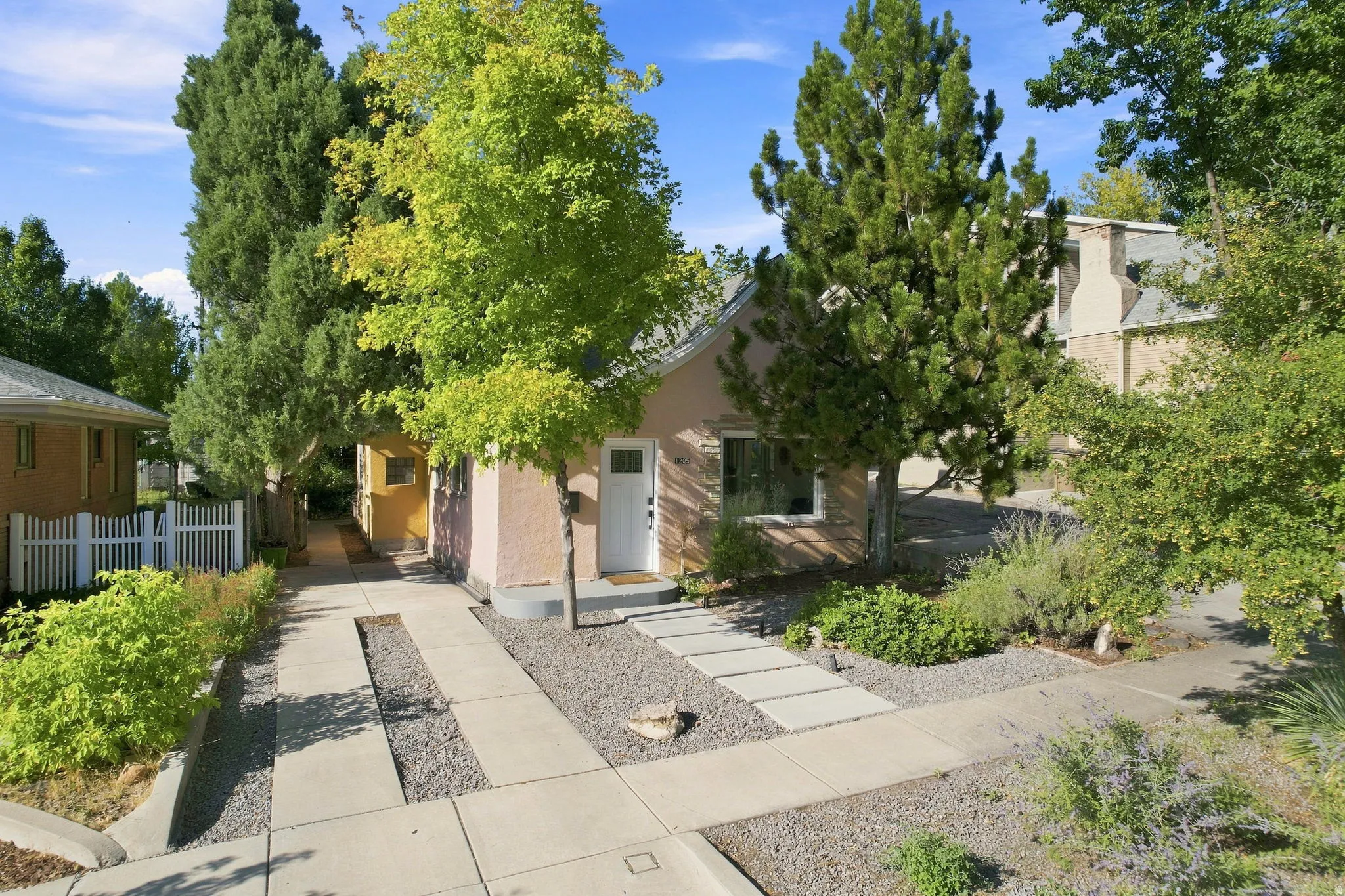 Stucco exterior with a pitched roof, front entry door, and a concrete pathway with stepping stones