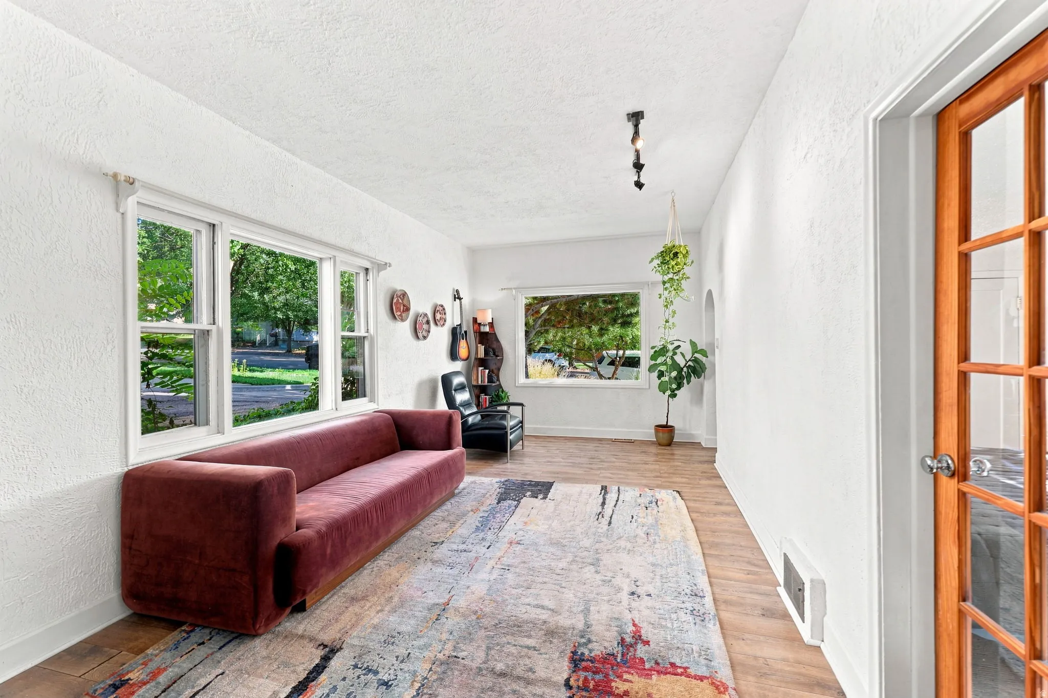 Wood-finish flooring, white painted walls, natural wood frame door with glass panes, white trim throughout, and recessed lighting