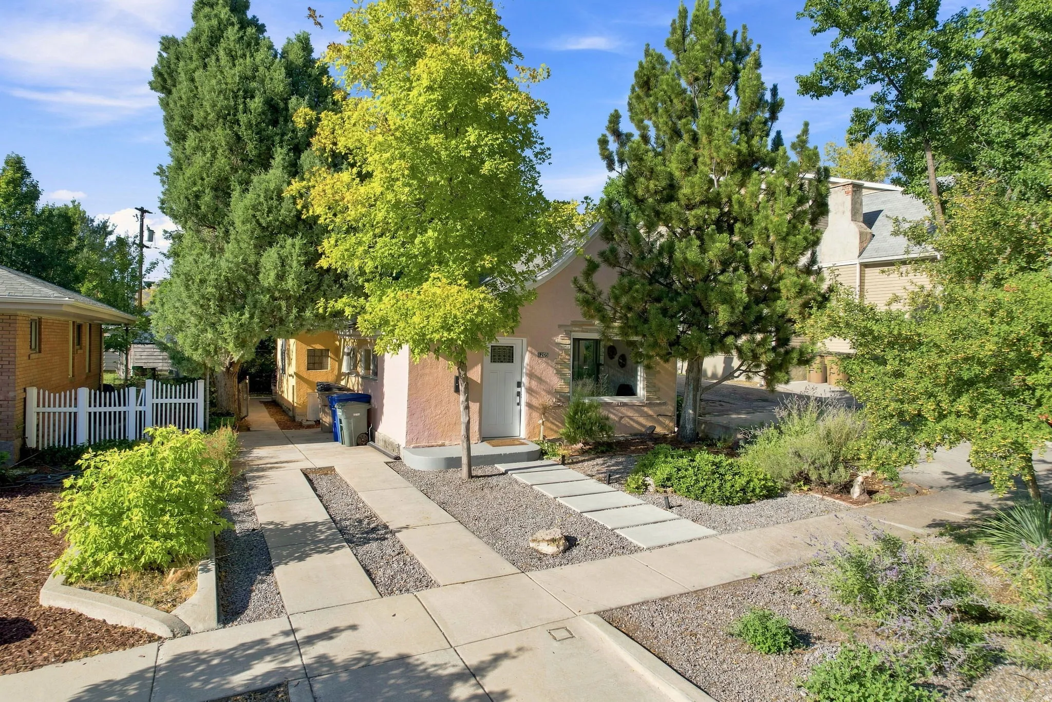 Stucco exterior with a white entry door, concrete drive, and a stone chip path