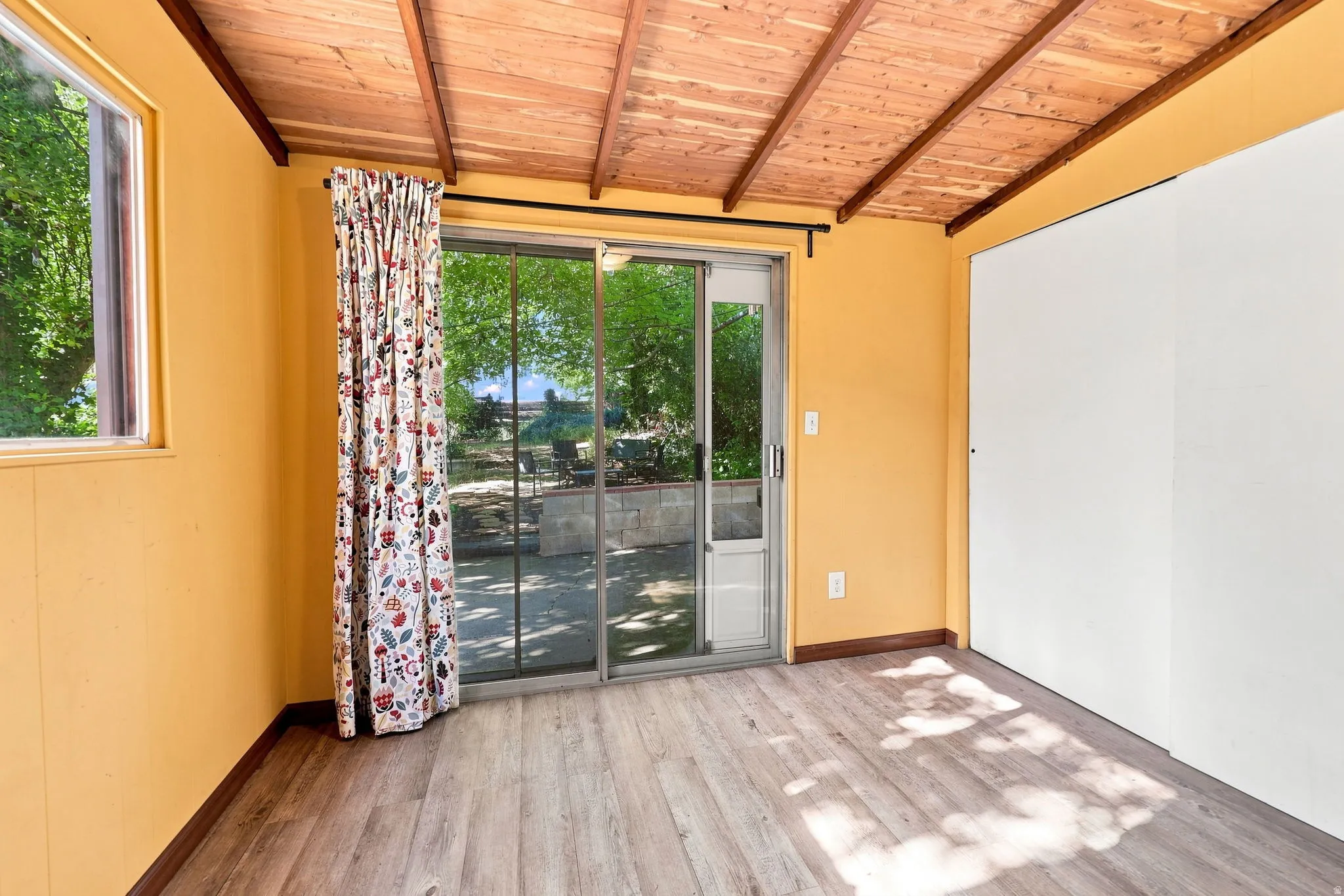 Wood-finish flooring, exposed wood beam ceiling, and a large sliding glass door