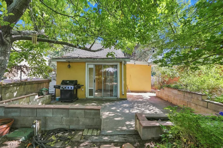 Poured concrete patio with block retaining walls, built-in fire pit, and mature shade trees