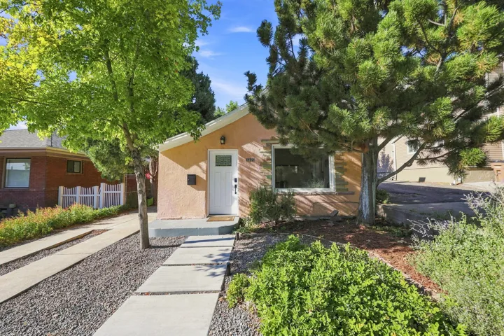 Stucco exterior with a white entry door, an accent window, and a concrete paver walkway