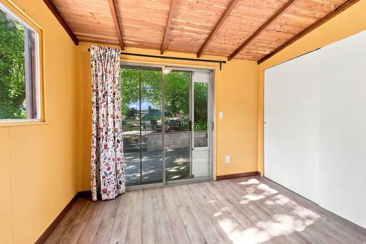 Wood-finish flooring, exposed wood beam ceiling, and a large sliding glass door