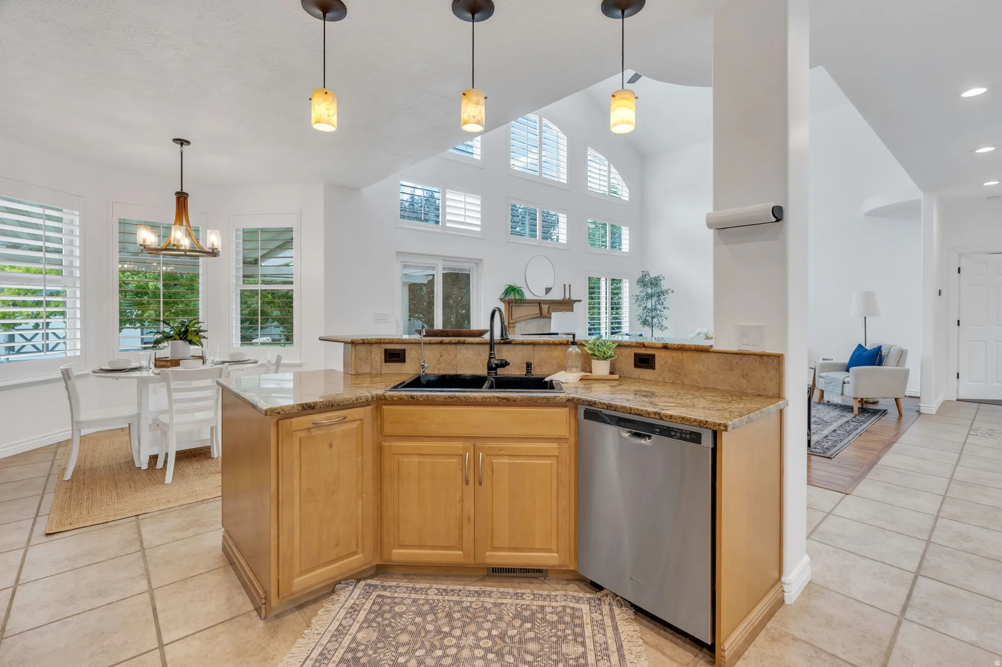 Kitchen featuring light wood cabinetry, granite countertops, a built-in stainless steel dishwasher, and a black sink with a gooseneck faucet