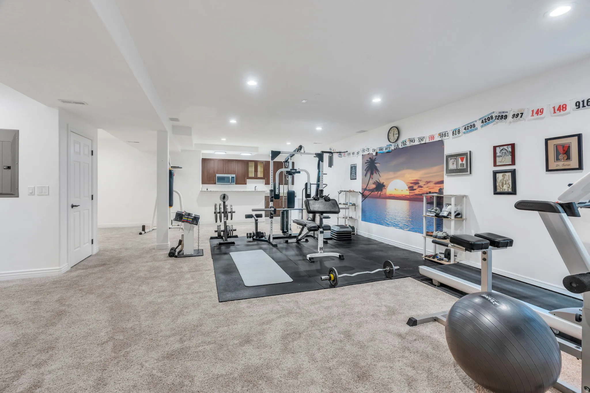 Spacious room with recessed lighting, light-toned carpet flooring, white walls, and a built-in wet bar featuring dark wood-finish cabinetry
