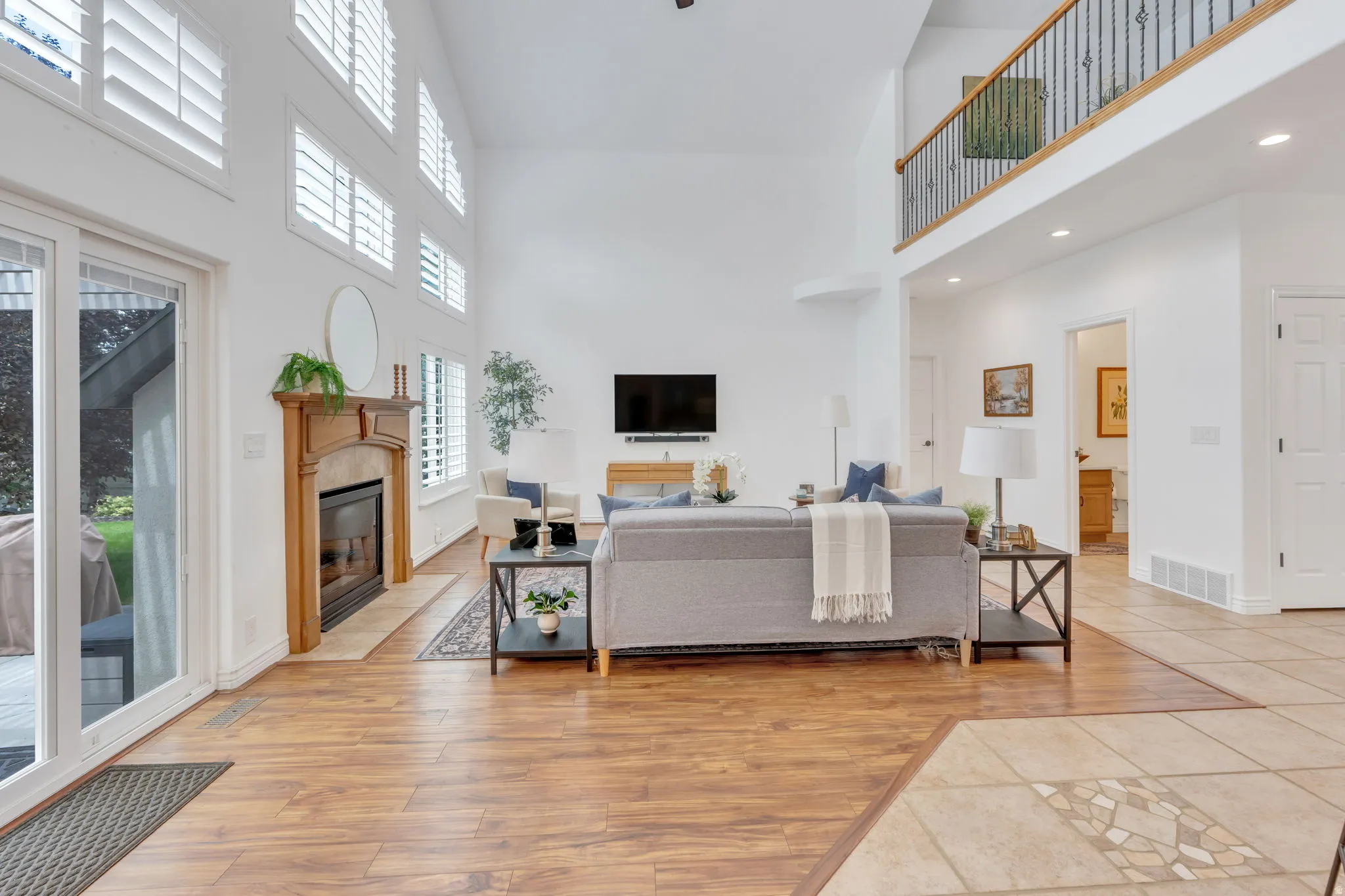 Spacious living area featuring a vaulted ceiling, wood-finish flooring, and a fireplace with a wood mantle