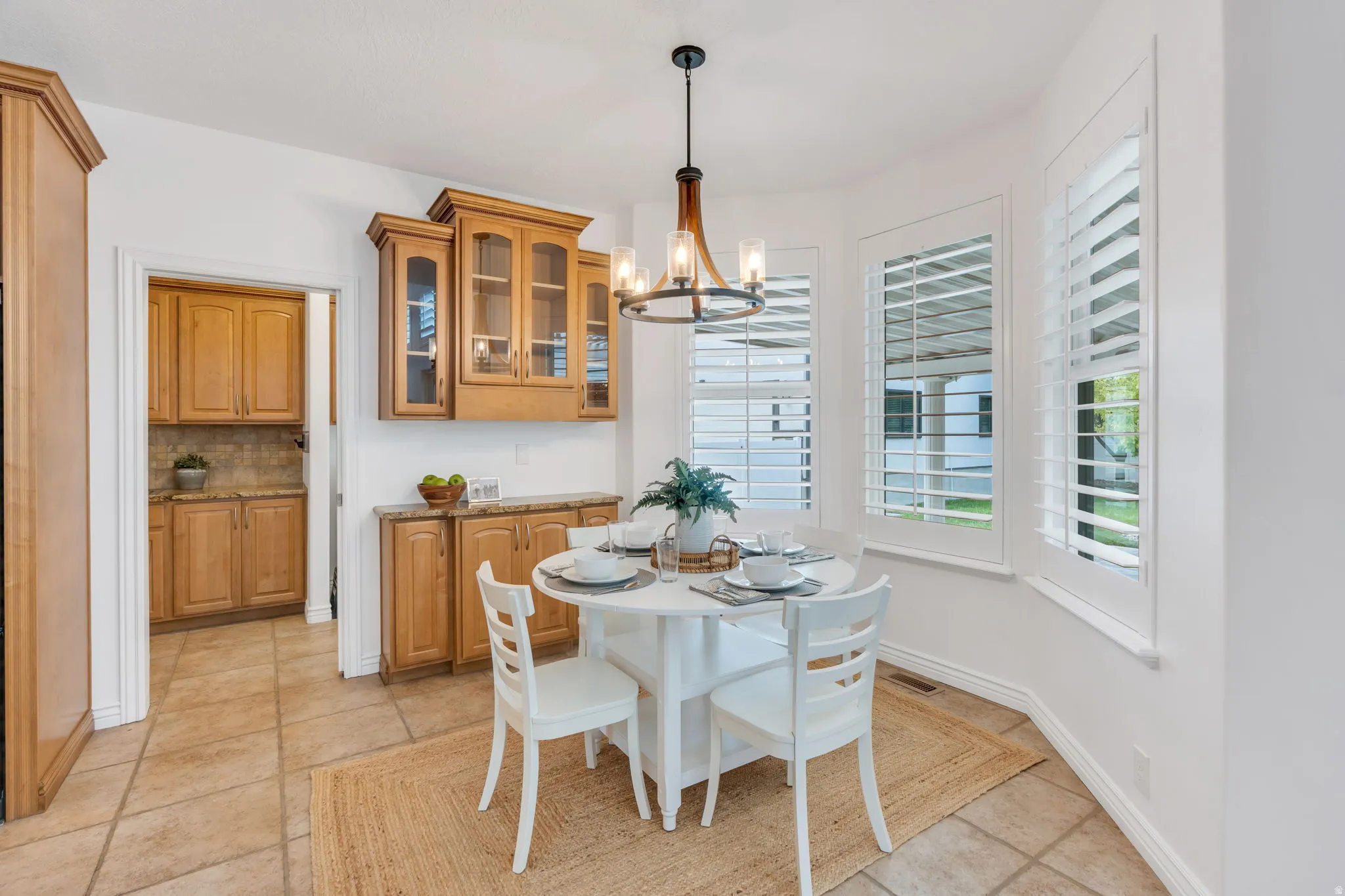 Custom cabinetry with glass-front uppers, tile flooring, and custom plantation shutters