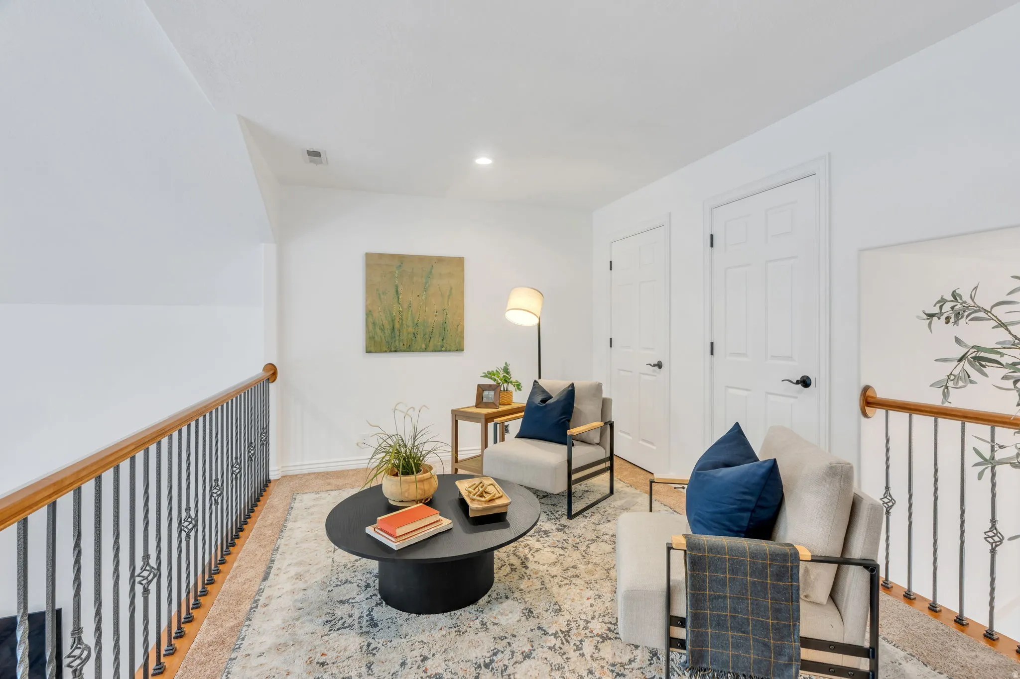 Carpeted loft area with recessed lighting, white paneled doors, and a decorative wrought iron and wood handrail