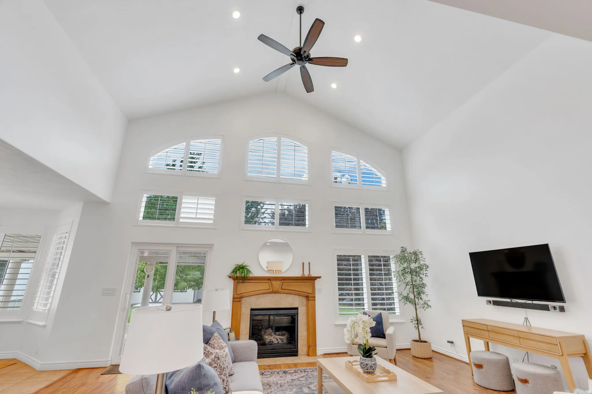 Vaulted ceilings with recessed lighting, wood-finish flooring, a fireplace with a wood mantle, and sliding glass doors