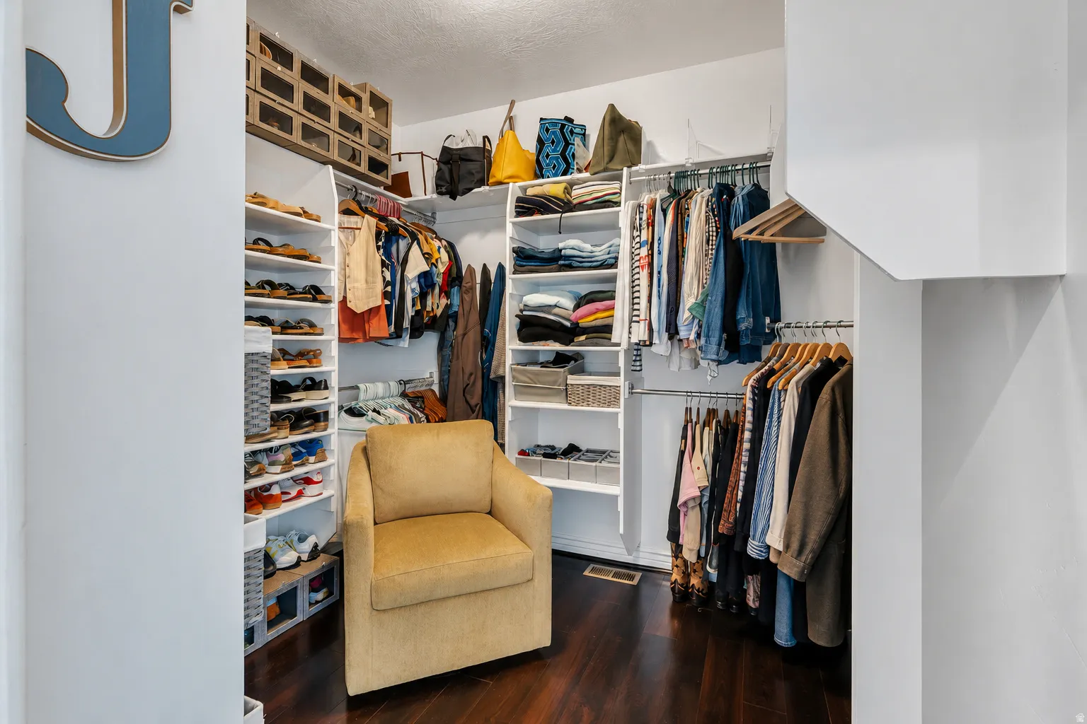 Hardwood-finish flooring, built-in shelving, multiple hanging rods, and integrated overhead storage