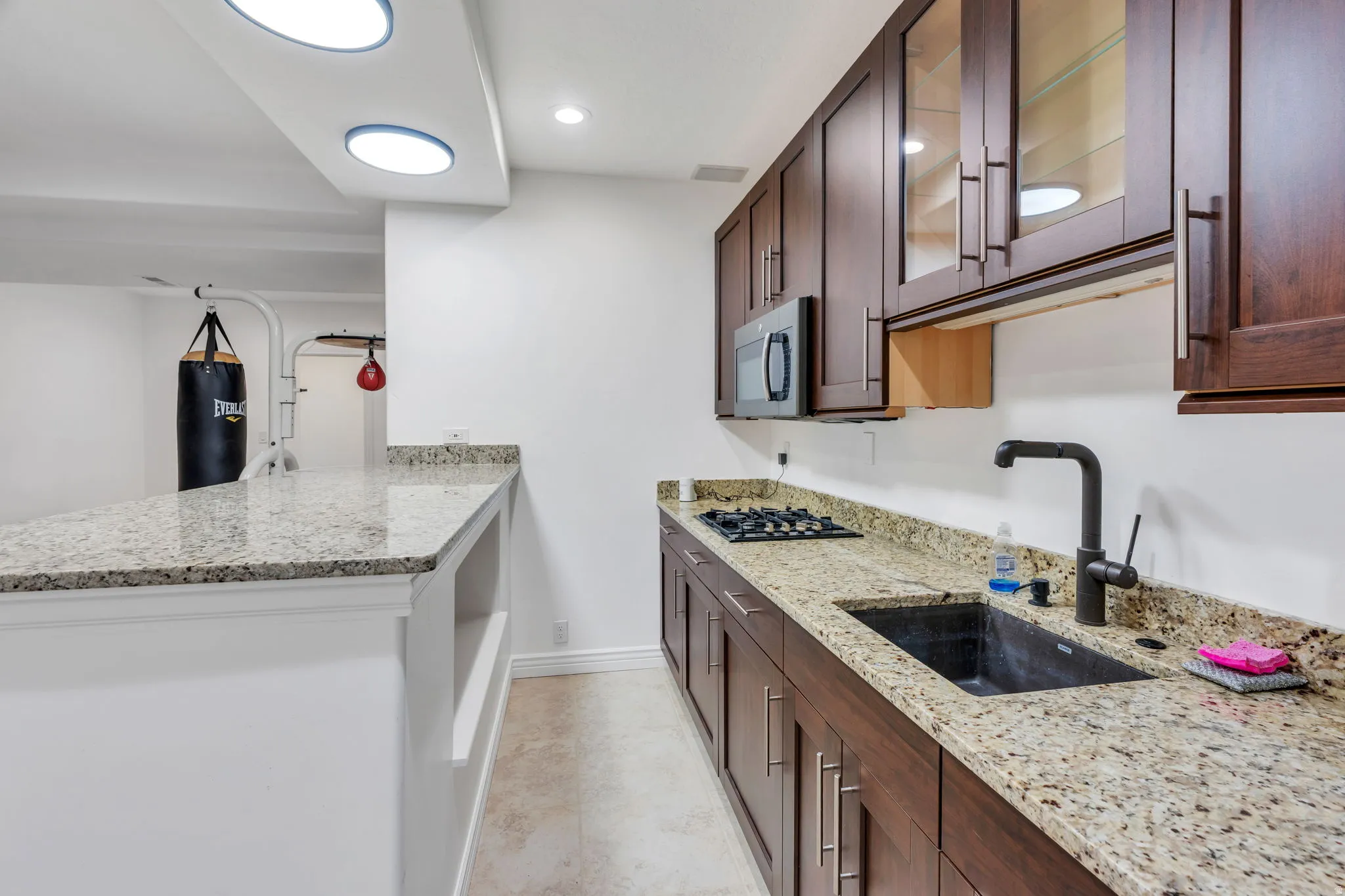 Kitchenette featuring a gas cooktop, built-in microwave, wood-finish cabinetry, and solid surface countertops