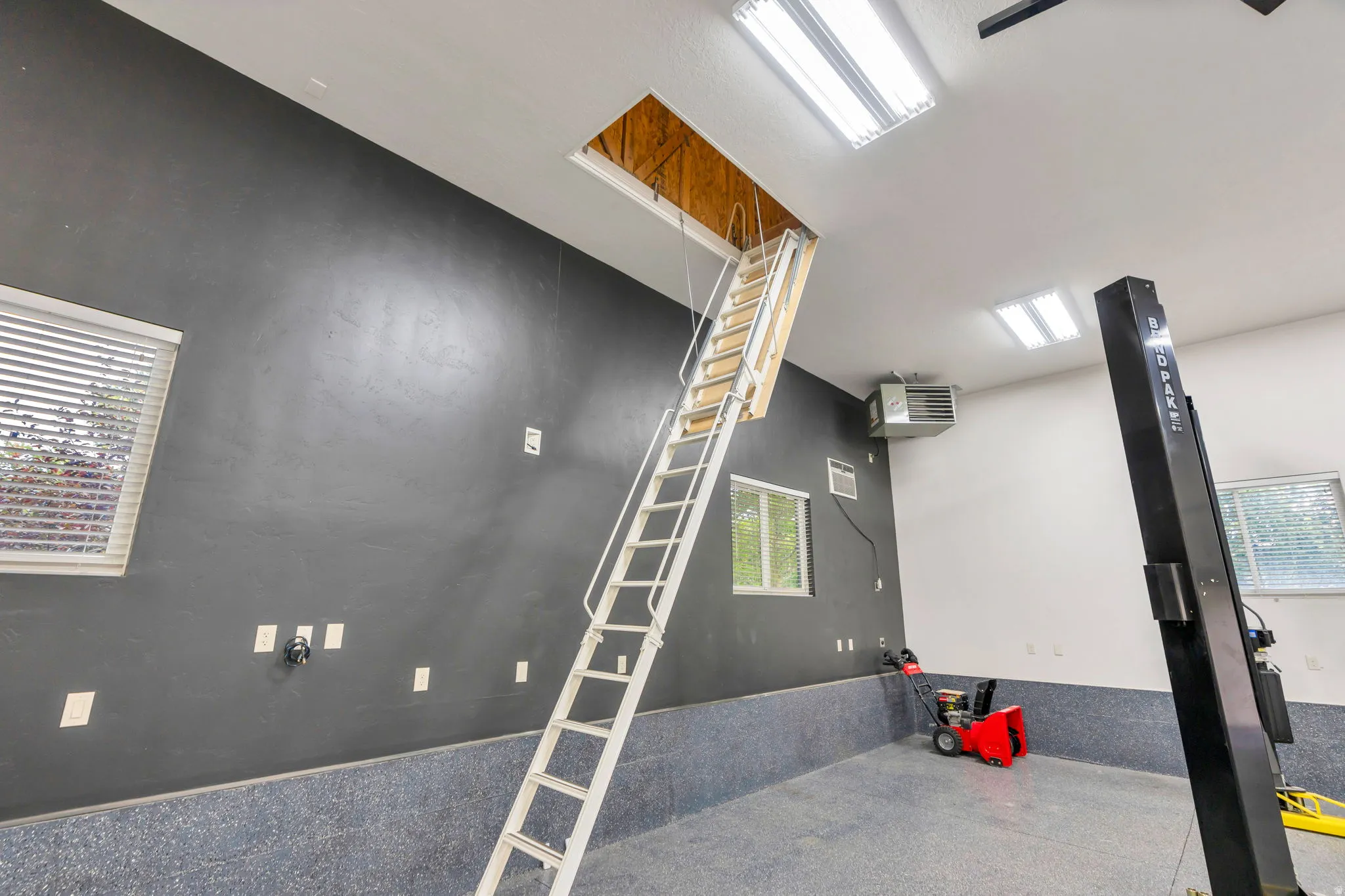 Detached garage with epoxy flooring, multiple windows, and fluorescent lighting