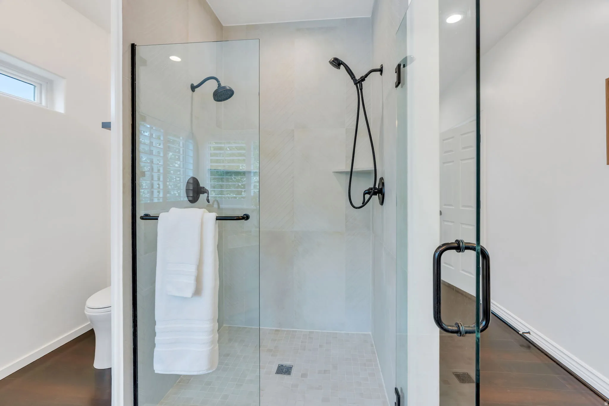 Walk-in shower with tile surround, glass enclosure, and black-finish fixtures