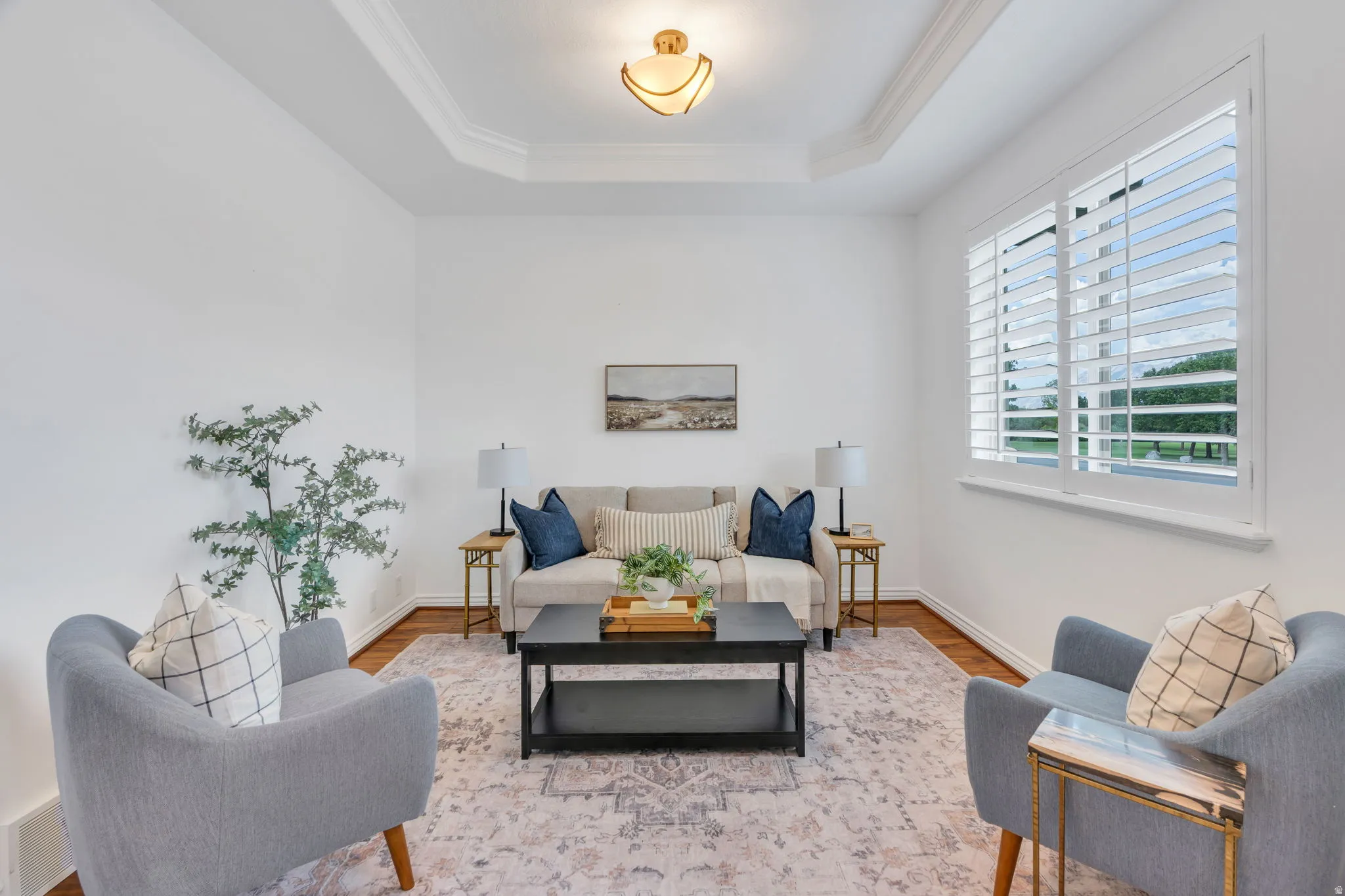 Tray ceiling with crown molding, recessed lighting, wood-finish flooring, and white plantation shutters