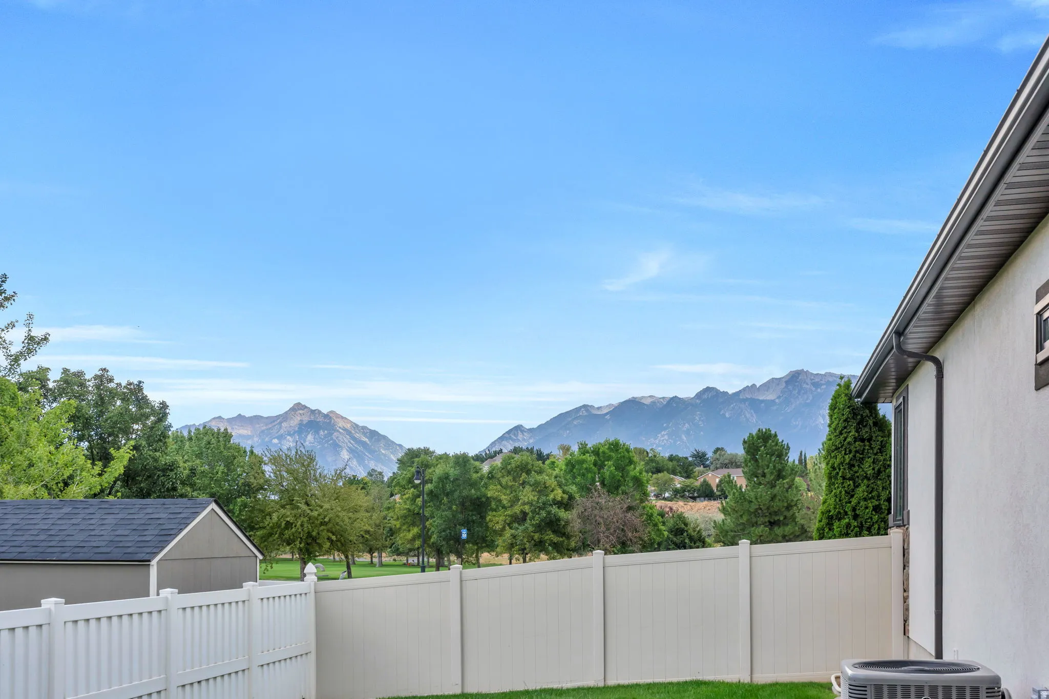 Private yard featuring a white privacy fence, a stucco exterior, and distant mountain scenery
