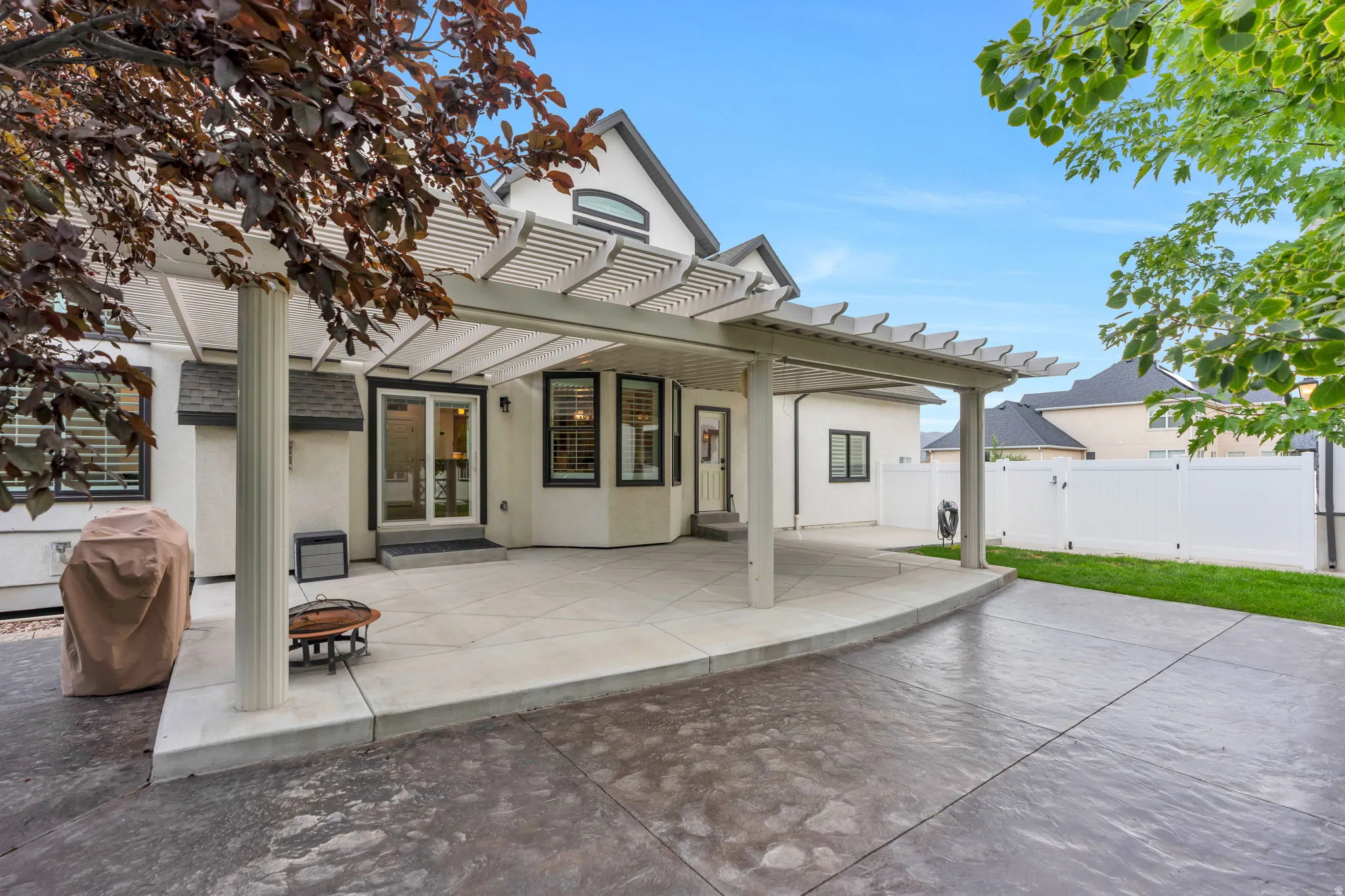 Exterior patio with a pergola, concrete hardscaping, manicured lawn, and privacy fencing