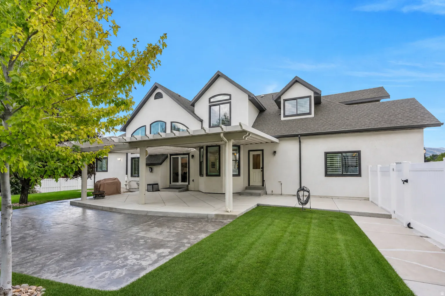 Beautiful backyard living with an expansive covered patio, mature shade trees, lush lawn, and plenty of space to relax, entertain, and enjoy Utah’s beautiful seasons.