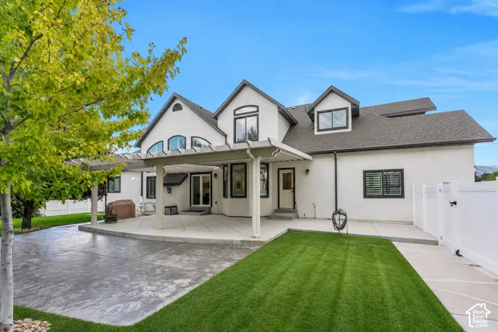 Beautiful backyard living with an expansive covered patio, mature shade trees, lush lawn, and plenty of space to relax, entertain, and enjoy Utah