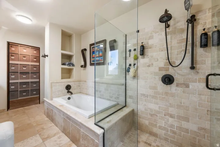 Walk-in shower with natural stone tile, glass enclosure, and matte black fixtures