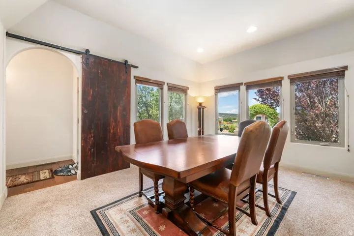 Carpeted flooring with an arched doorway and a barn door