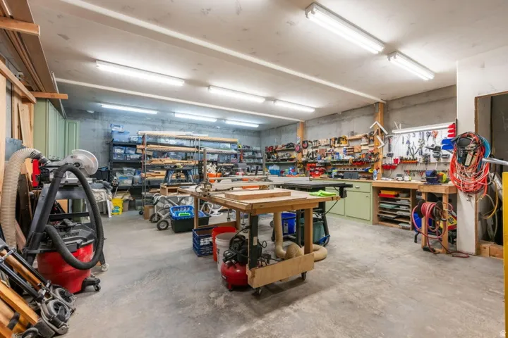 Spacious workshop featuring a concrete floor, built-in shelving, wall-mounted tool organization, and ample overhead lighting