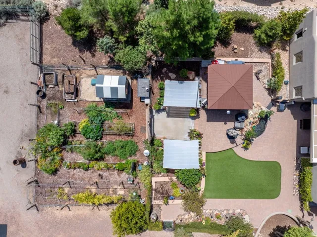 Expansive exterior space featuring a large garden area, multiple shade structures, a paved patio, and an artificial turf lawn