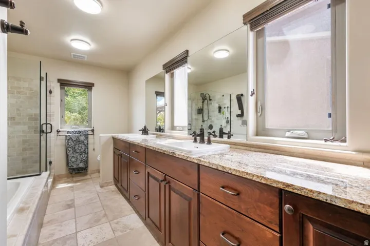 Dual vanity with stone countertop, rich wood-finish cabinetry, and undermount sinks