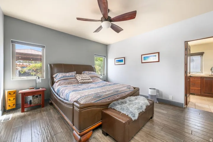Vaulted ceiling with an attached ceiling fan, wood-finish flooring, and recessed windows