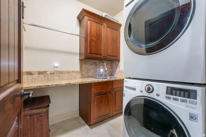 Built-in cabinetry, granite-style countertop, tiled backsplash, and stainless steel sink