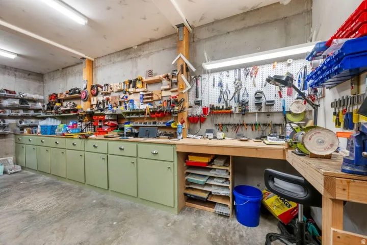 Built-in cabinetry with light-colored countertops, pegboard wall organization, and exposed wood beam accents